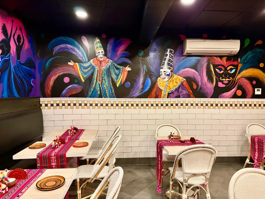 Mural of Andean festival dancers above the tables